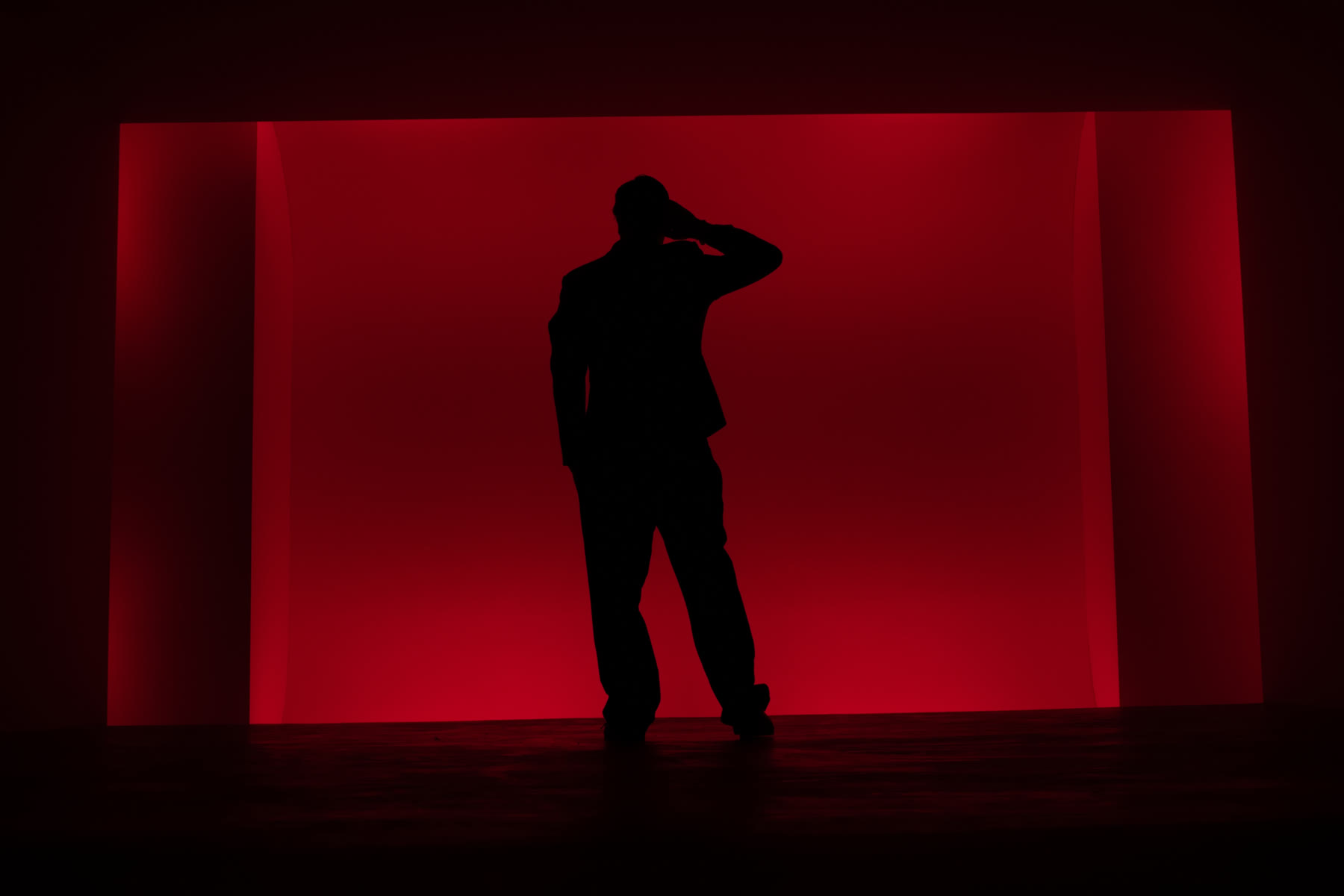 Sinan in silhouette against a red-lit wall